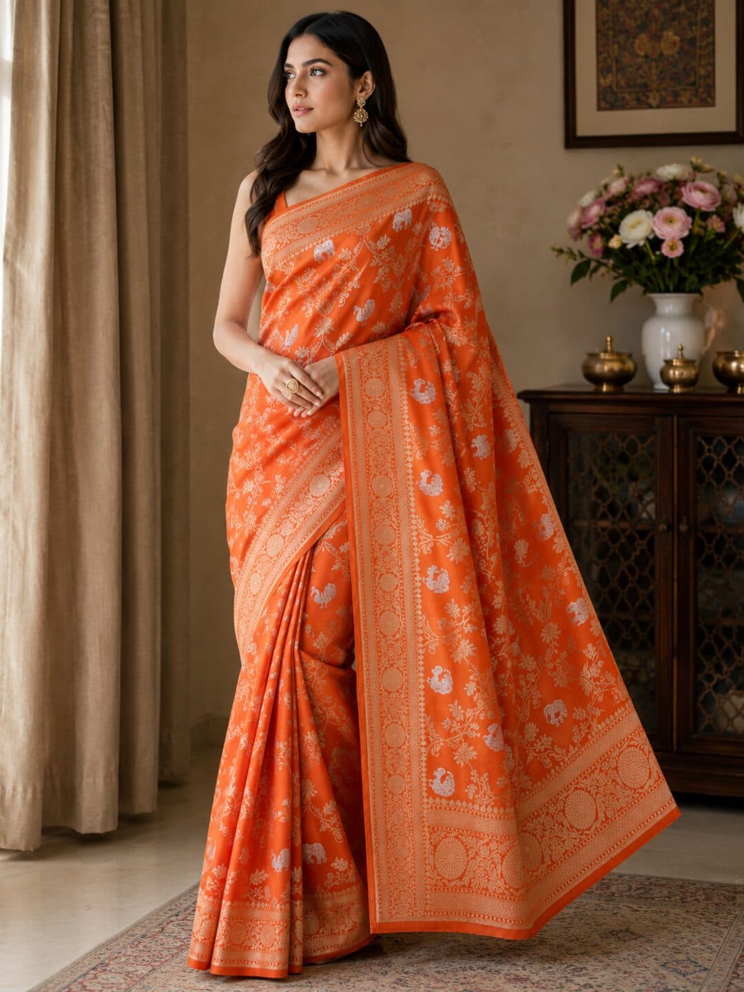 Orange Banarasi silk saree woven with silver elephants and peacocks inside a trellis of gold vines