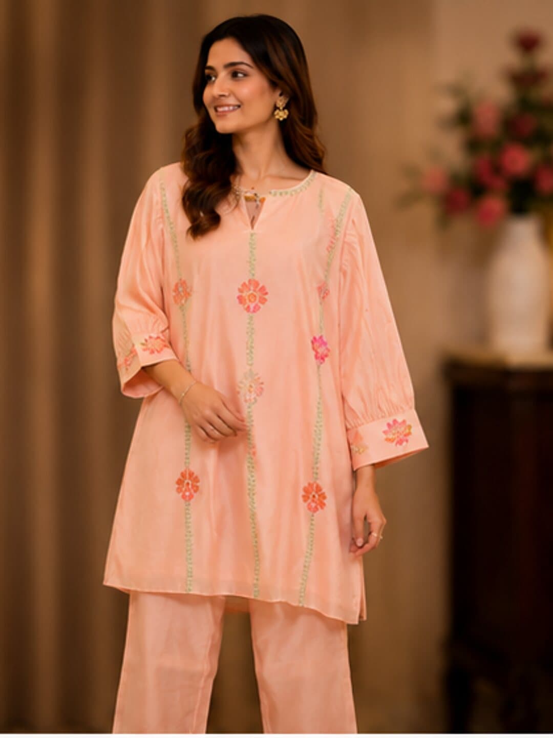 Peach kurta with green embroidered vines running its length and small orange flower butis between them