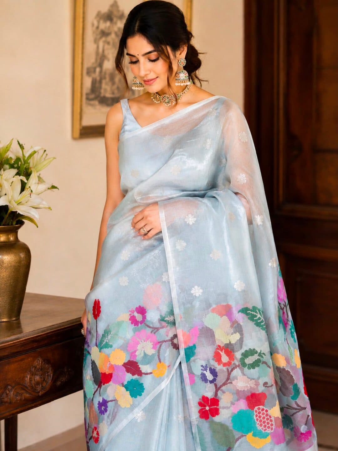 Powder blue silver tissue organza saree scattered with small silver flowers, with a multicolour jamdani vine of blossoms and pomegranates worked along the lower border